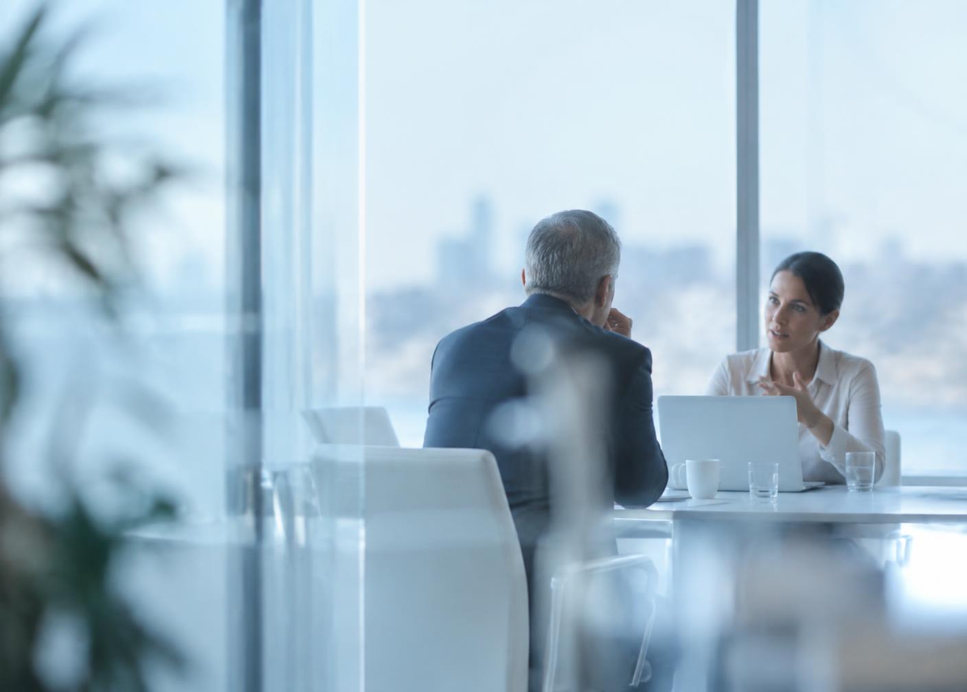 Two executives in a bright meeting room, mid-conversation